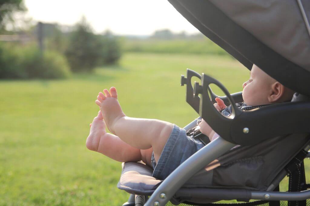 Do you need a stroller in Hawaii? Image of a baby with chunky legs in a stroller in the sunshine.