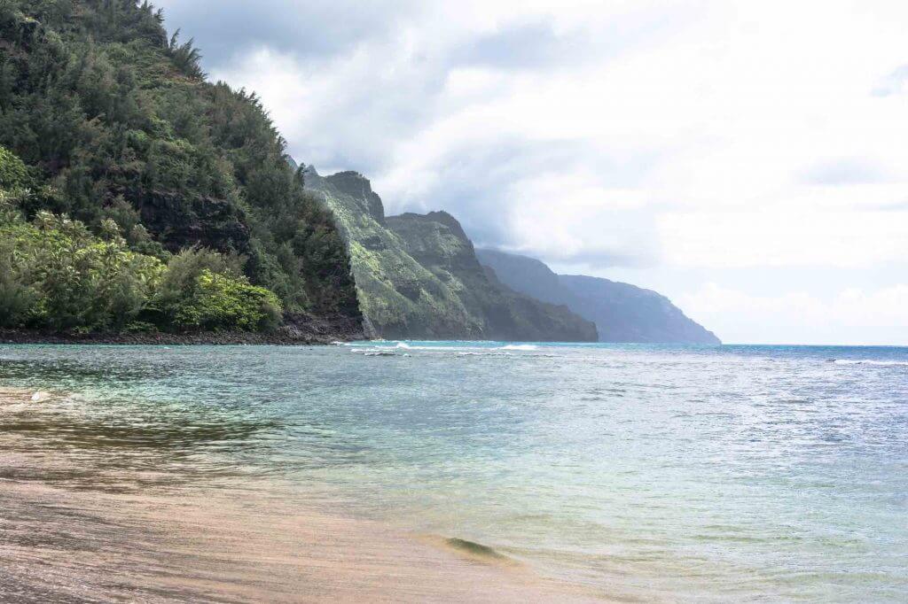 Kee Beach is a popular snorkeling Kauai beach at the end of the road on Kauai. Photo of the calm water and Na Pali Coast in the background.