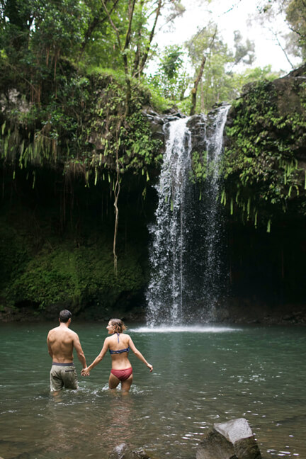 Twin Falls, Maui, Hawaii--Twin Falls is one of the best Maui waterfalls for kids. Image of a couple holding hands while wading into the waterfall.