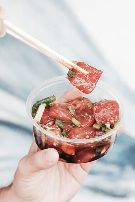 Oahu poke places are all the rage because they are usually portable like this one. Image of a plastic container filled with chopped up raw fish.