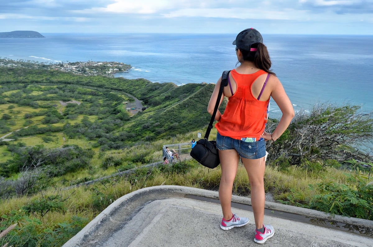 Find out the best easy hikes on Oahu by top Hawaii blog Hawaii Travel with Kids. Image of a woman wearing a red tank top standing at the end of a hike on Oahu