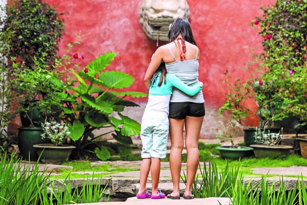 Things to Do in Hawaii with Kids: a review of Honolulu Museum of Art on Oahu featured by top Hawaii blog, Hawaii Travel with Kids: image of Girls hugging in the Asian Courtyard at the Honolulu Museum of Art on Oahu