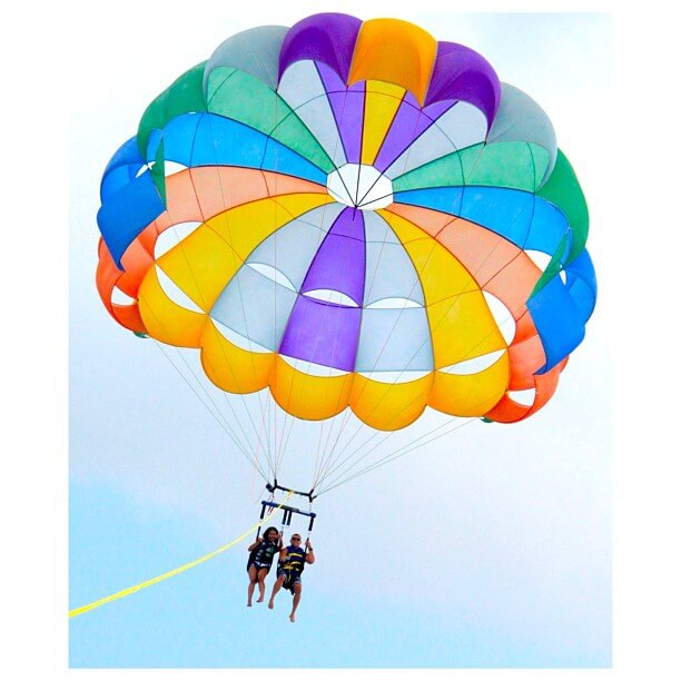 A couple parasailing in a colorful parachute in Hawaii