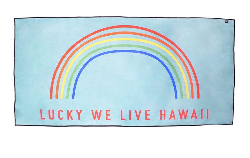 Top 15 Best Kauai Souvenirs featured by top Hawaii blog, Hawaii Travel with Kids: Travel towel with a rainbow that says "Lucky We Live Hawaii."