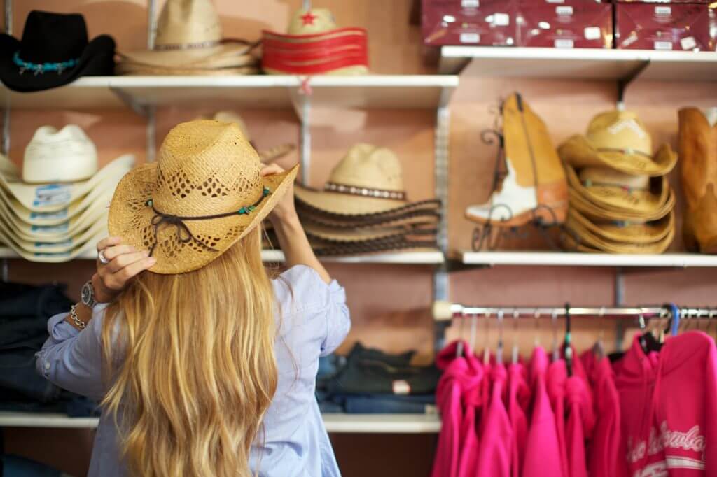 Woman trying on hats while shopping in Makawao, Maui