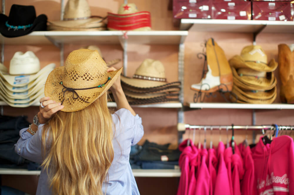 The Ultimate Guide to Shopping on Maui featured by top Hawaii blog, Hawaii Travel with Kids: Woman trying on hats while shopping in Makawao, Maui