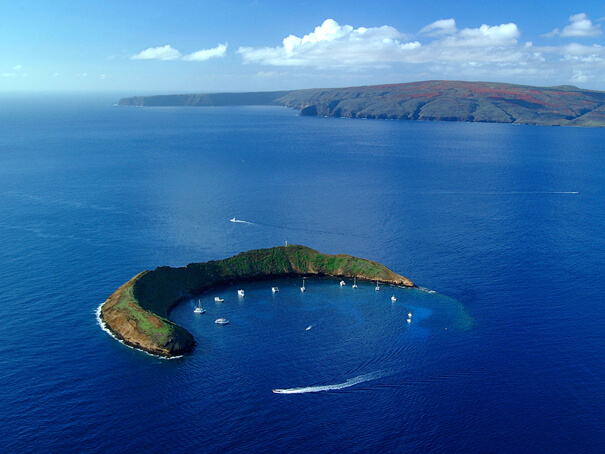 Exploring Molokini Crater in Maui is a top thing to do in Hawaii with kids. Image of a crescent shaped islet in Hawaii.