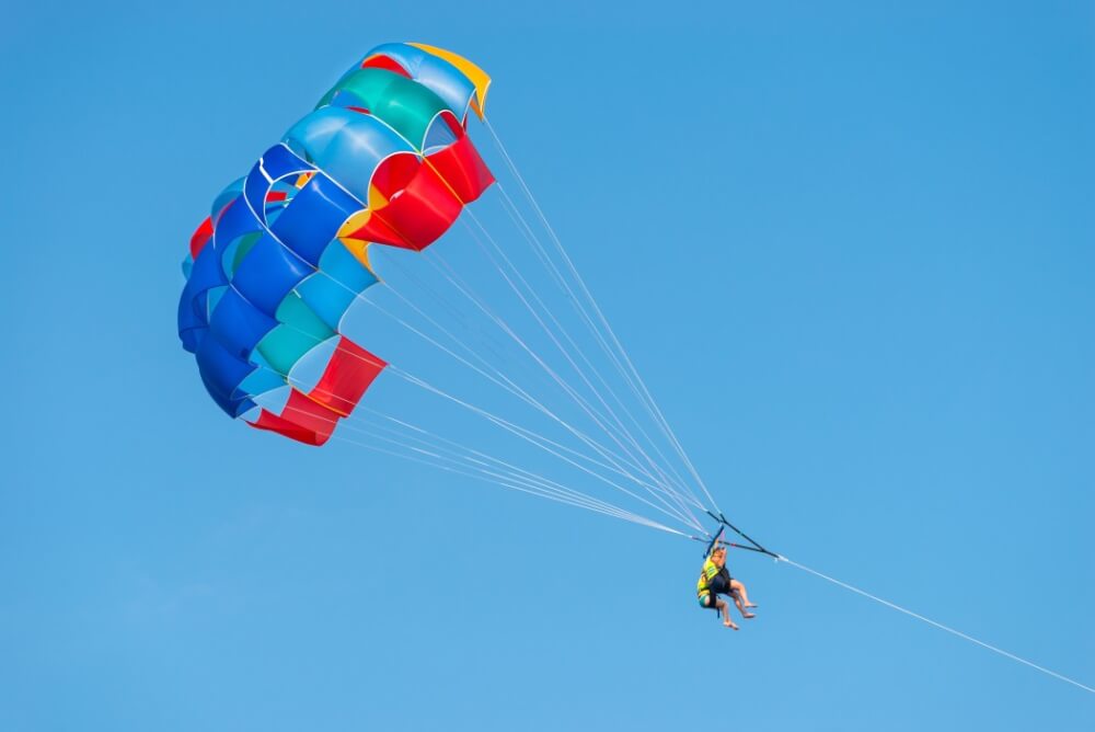 6 Best Places to Go Parasailing on Maui featured by top Hawaii blog, Hawaii Travel with Kids: Man parasailing in Hawaii