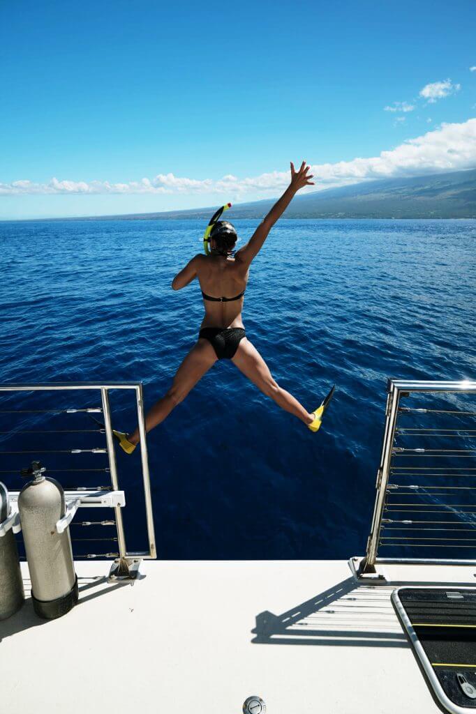 Woman jumping off boat near Molokini Crater in Maui