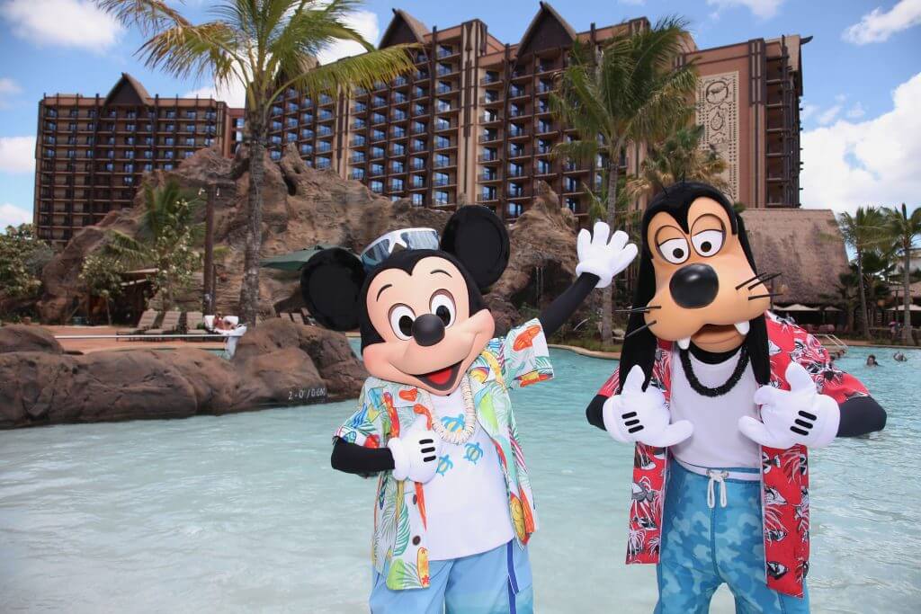 Disney's Aulani Resort is one of the best Hawaii family hotels with an incredible kids club that's totally free! Image of Mickey and Goofy wearing Aloha shirts in front of the resort pool.