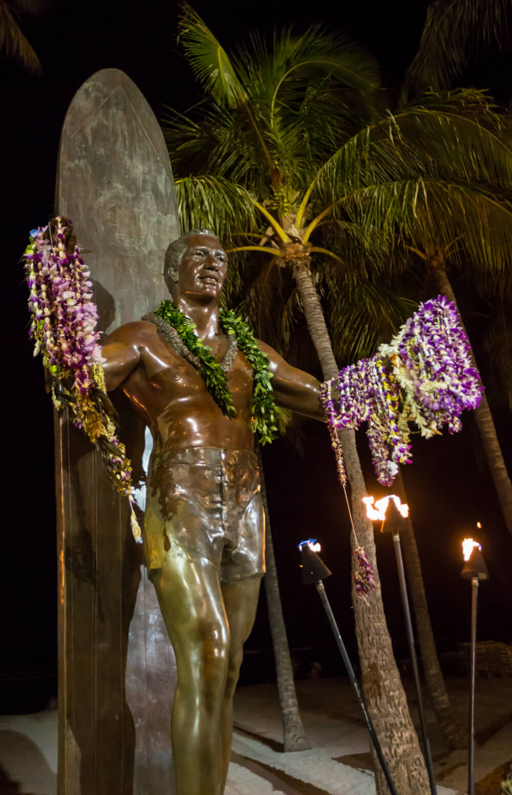 25 Amazing activities in Waikiki with kids featured by top Hawaii blog, Hawaii Travel with Kids: Duke Kahanamoku statue at night.