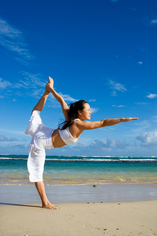 Image of a woman doing yoga on the beach maui