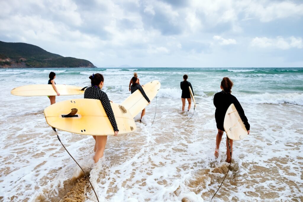 People holding surfboards heading to the ocean