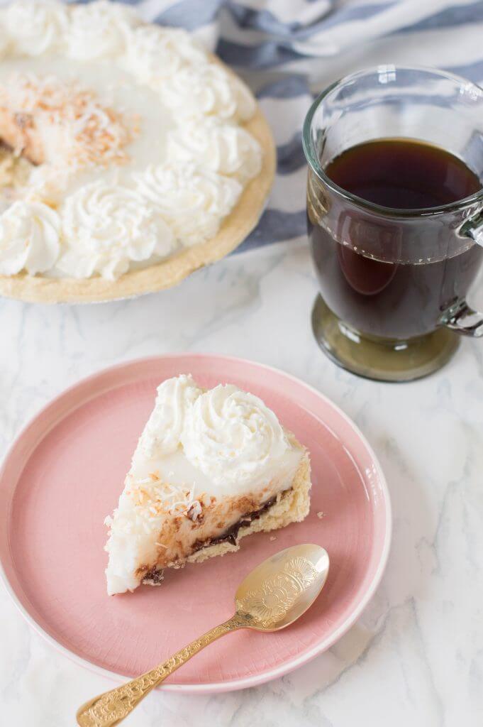 Get this Chocolate Haupia Pie Recipe (aka one of the best Hawaiian dessert recipes) by Top Hawaii Blog Hawaii Travel with Kids. Image of a slice of chocolate coconut cream pie with a cup of coffee.