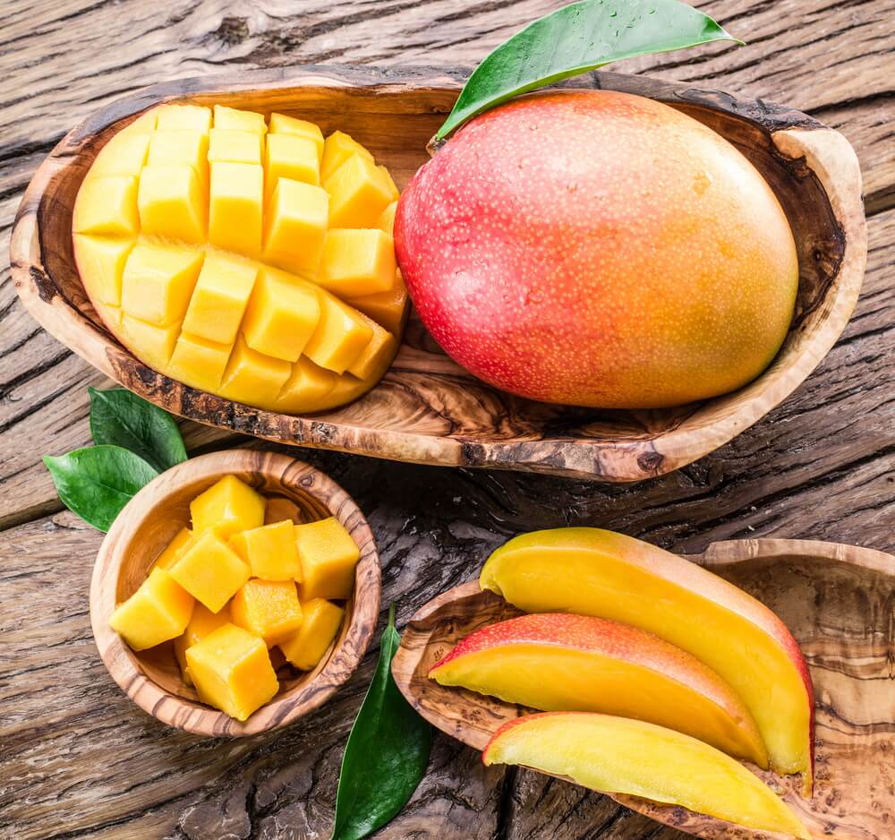 Mango fruit and mango cubes on the wooden table.