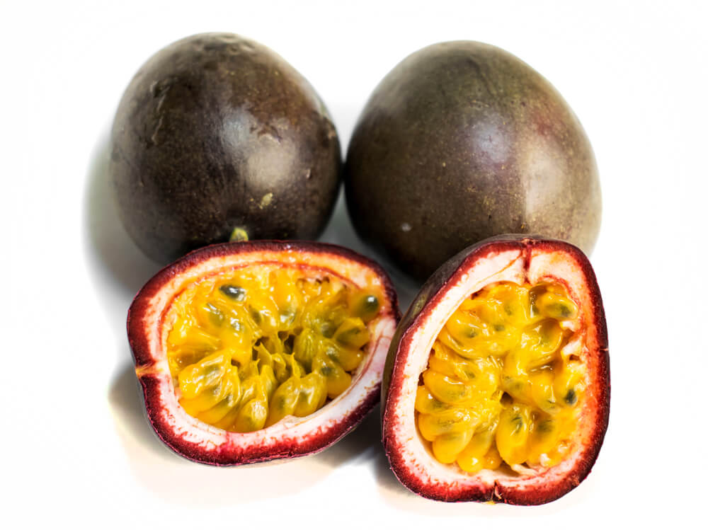 Passion fruit ( Passiflora edulis).3 fruits. The fruit is cut in two halves. Isolated on a white background