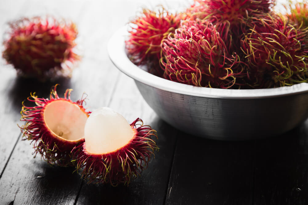 15 Hawaiian Fruits to Try featured by top Hawaii blog, Hawaii Travel with Kids: Fresh rambutan on wooden table background