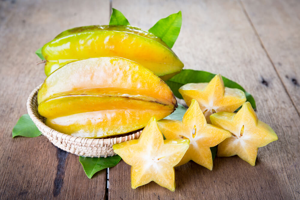 15 Hawaiian Fruits to Try featured by top Hawaii blog, Hawaii Travel with Kids: Star fruit on wood background .