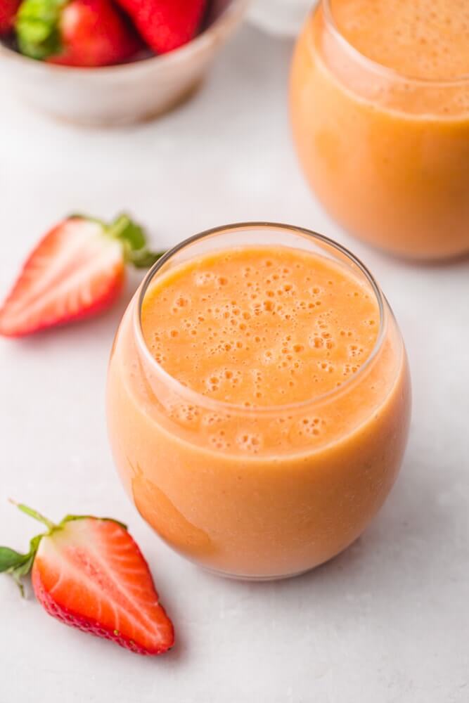 Hawaiian Tropical Smoothie Recipes to Make at Home featured by top Hawaii blog, Hawaii Travel with Kids: 2 glasses of strawberry mango smoothie and sliced strawberries