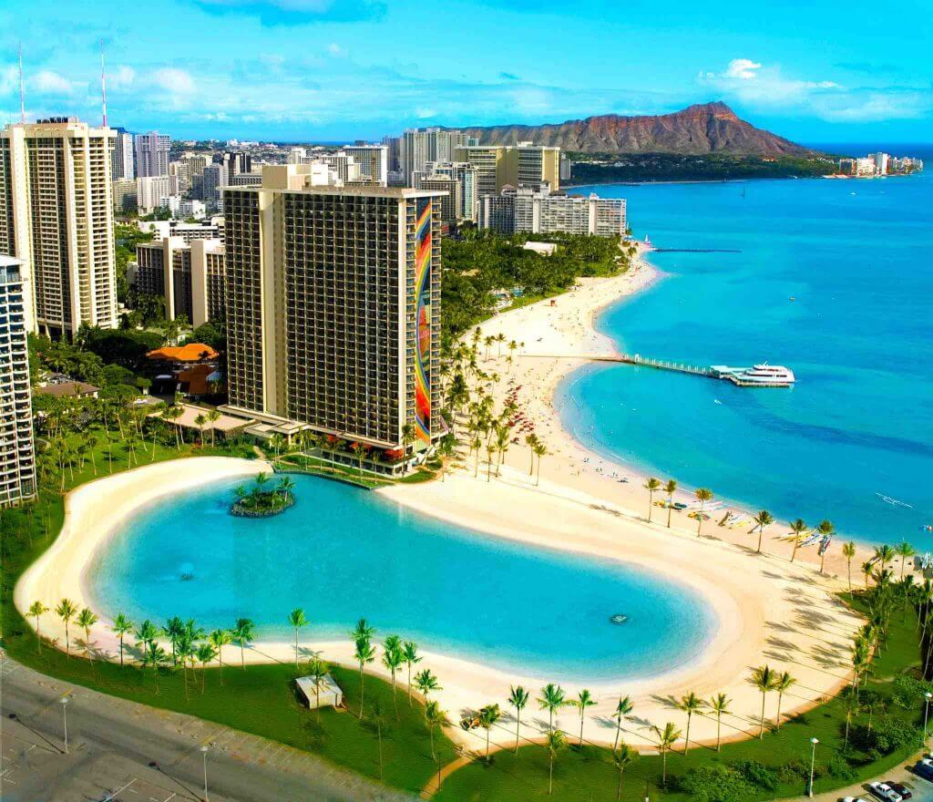 The Hilton Hawaiian Village is one of the Best Resorts in Oahu for Families. Image of Waikiki Beach and the pool area at the Hilton Hawaiian Village Oahu Resort.
