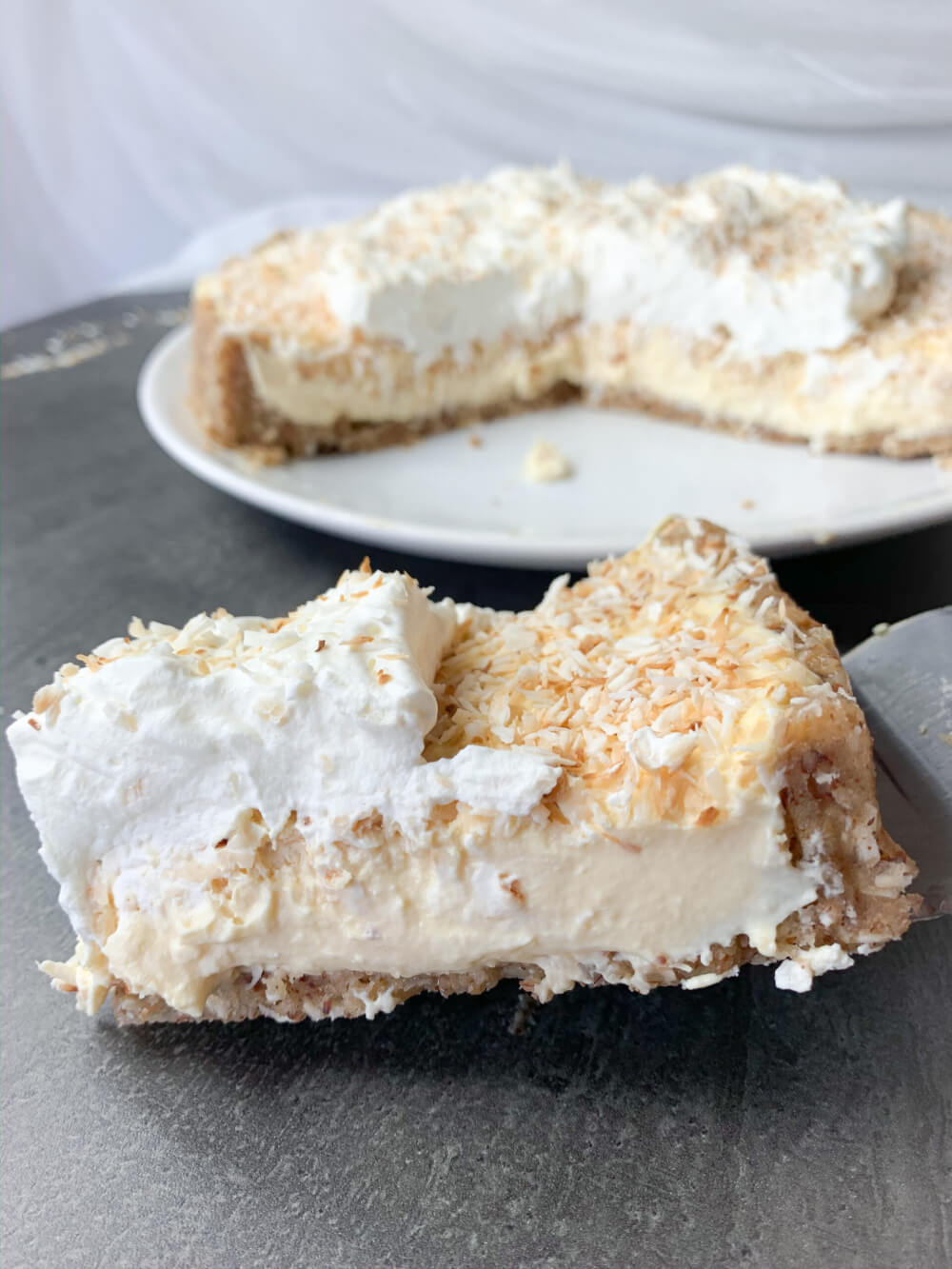 61 Delicious Coconut Dessert Recipes Perfect for Summer featured by top Hawaii blog, Hawaii Travel with Kids: Slice of low carb coconut cream pie with heavy whipping cream on top