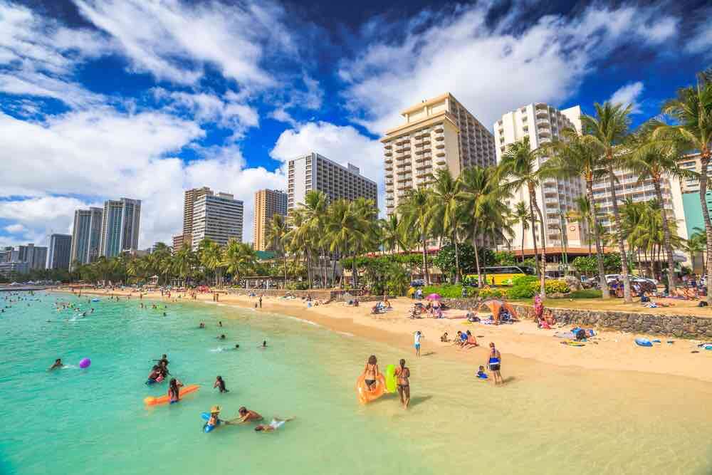 25 Amazing activities in Waikiki with kids featured by top Hawaii blog, Hawaii Travel with Kids: Waikiki, Oahu, HI - August 27, 2016: summertime in crowded Prince Kuhio Beach also called The Ponds because a concrete wall makes the water calm. Kuhio Beach is a section of Waikiki Beach.