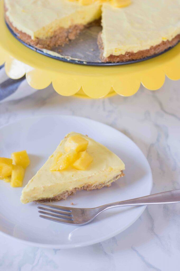 Find out how to make mango mousse cake by top Hawaii blog Hawaii Travel with Kids. Image of a slice of yellow mango mousse with diced mangoes on top.