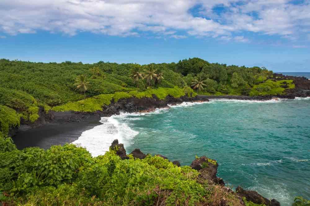 One of the best Road to Hana stops is the Waianapanapa State Park. Image of a Maui black sand beach.