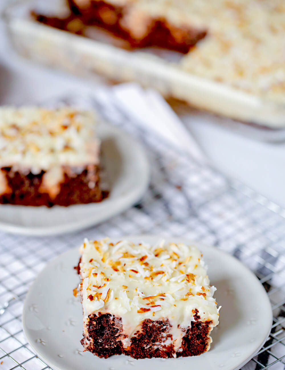 61 Delicious Coconut Dessert Recipes Perfect for Summer featured by top Hawaii blog, Hawaii Travel with Kids: chocolate coconut poke cake slice with toasted coconut