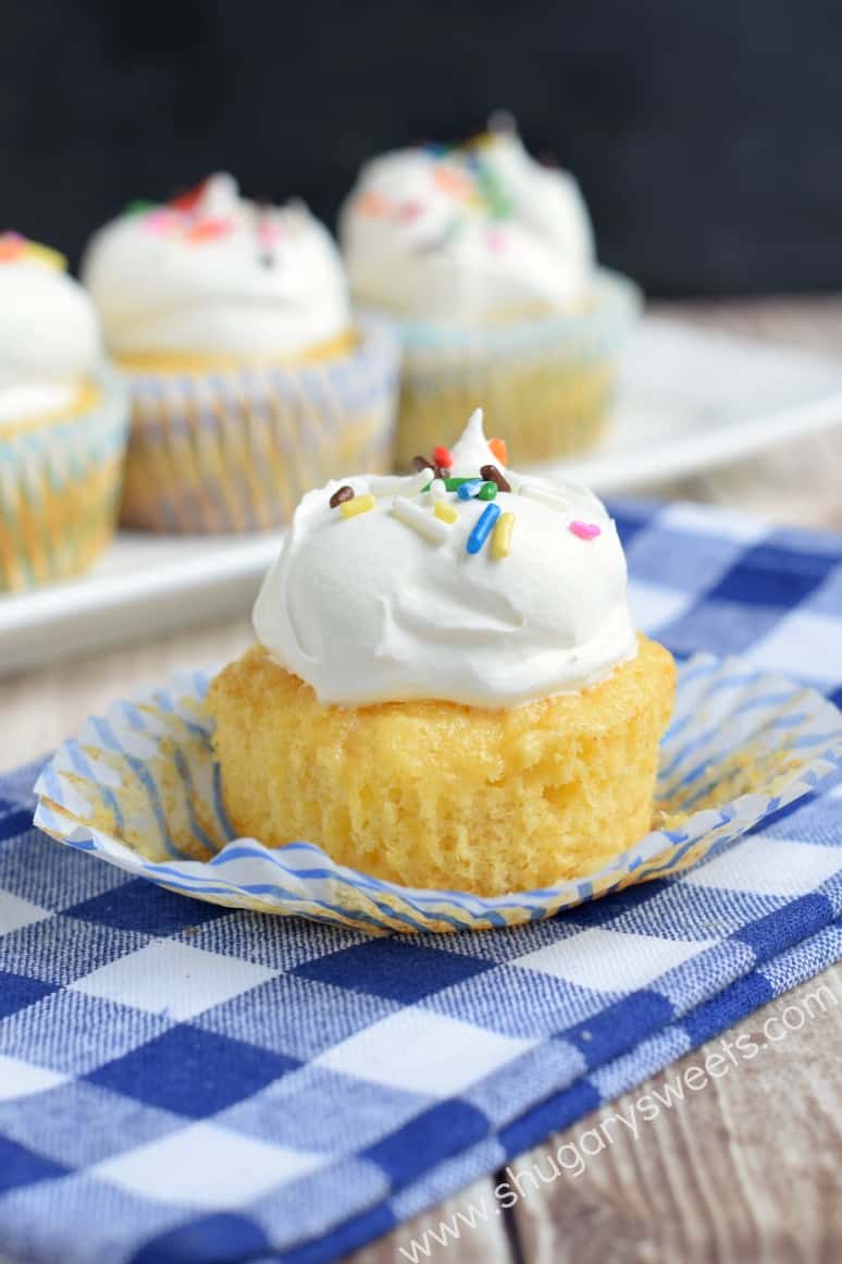 Pineapple Dessert Recipe Roundup by top Hawaii blog Hawaii Travel with Kids: Pineapple cupcake topped with whipped cream and sprinkles unwrapped on a blue checkered napkin.