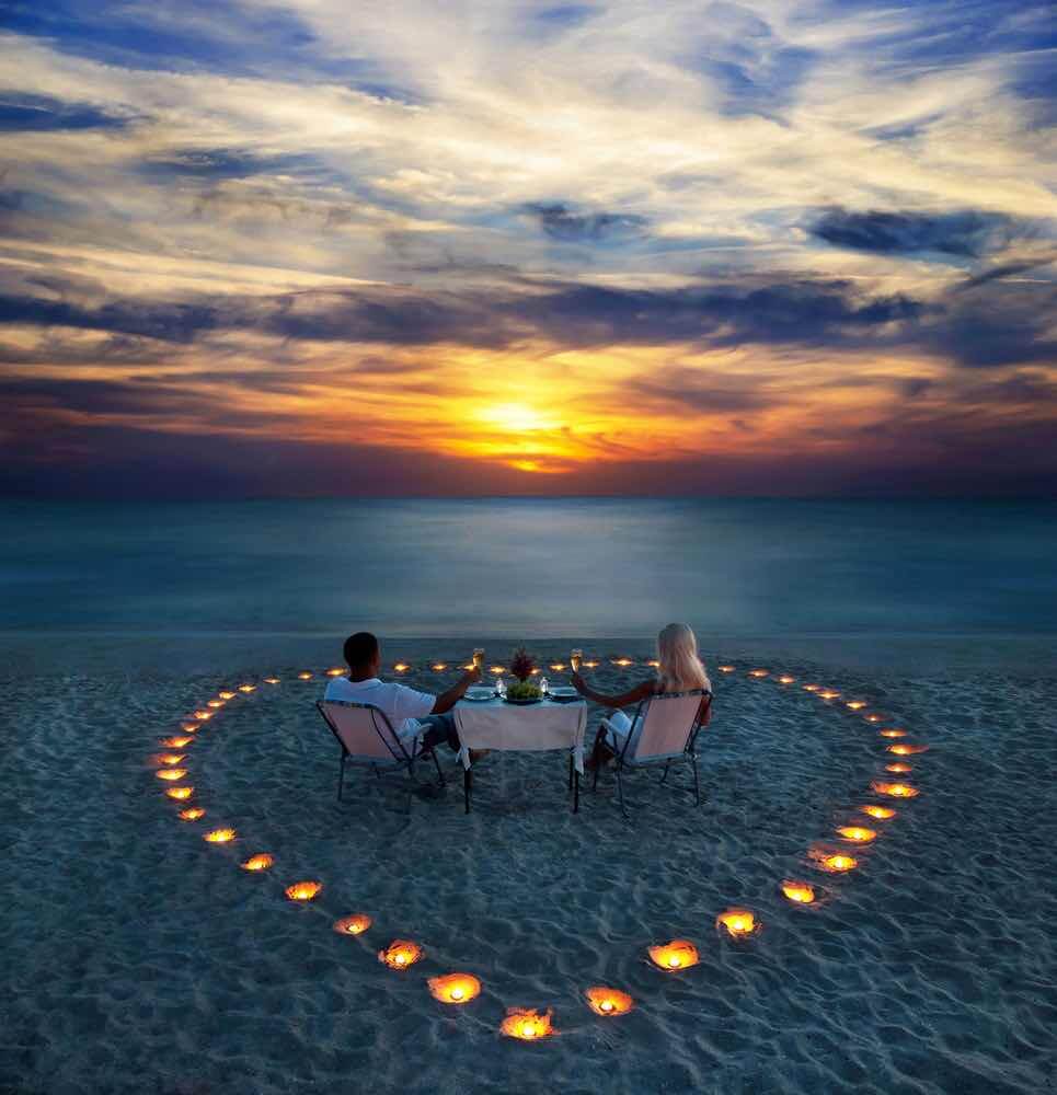 Top 10 Romantic Hawaii Beach Proposal Ideas + Locations featured by top Hawaii blog, Hawaii Travel with Kids: A young couple share a romantic dinner with candles heart on the sea sand beach