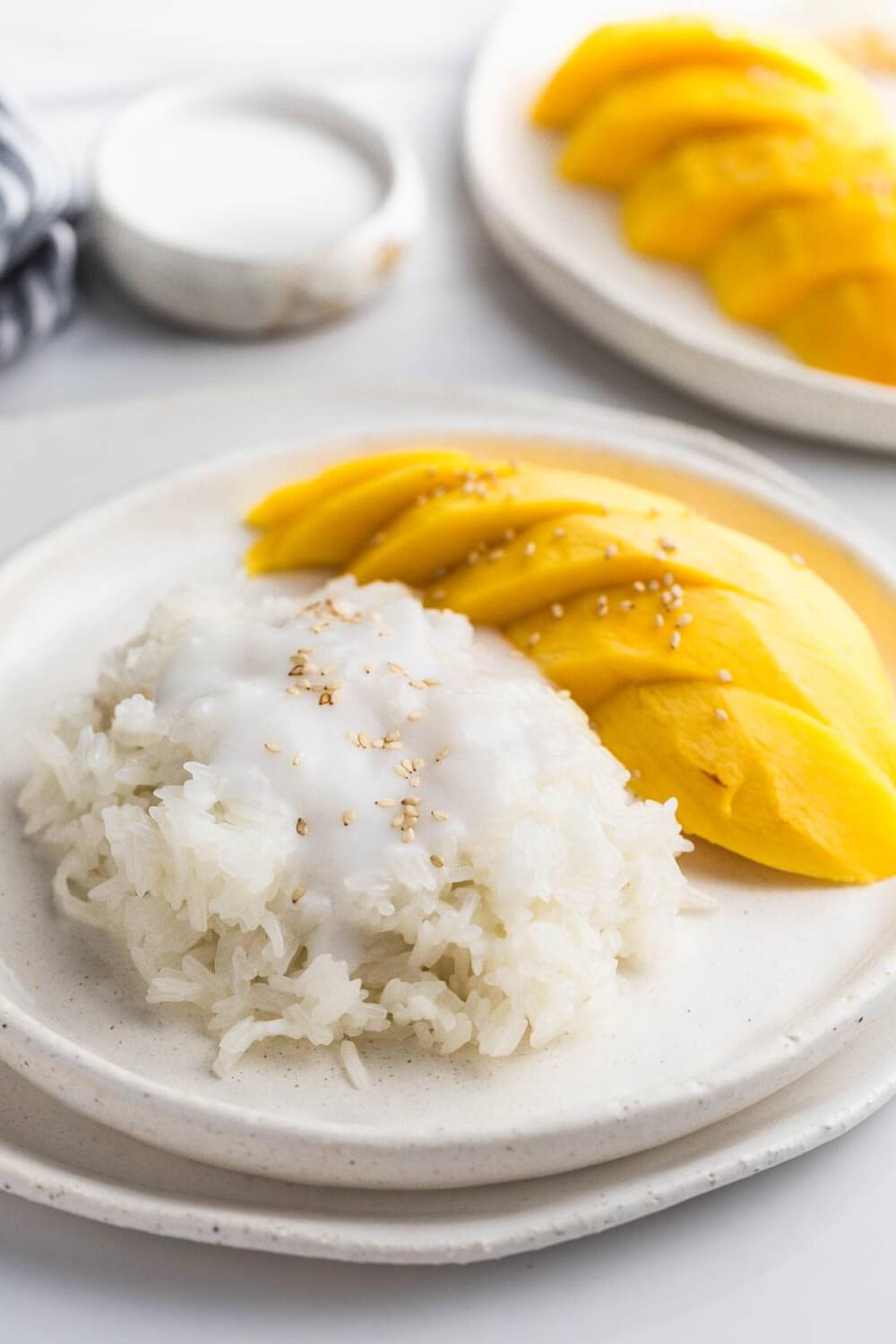 Best Mango dessert recipes by top Hawaii blog Hawaii Travel with Kids: Mango sticky rice, with fresh mango on the side on a white plate. On a white ceramic tray