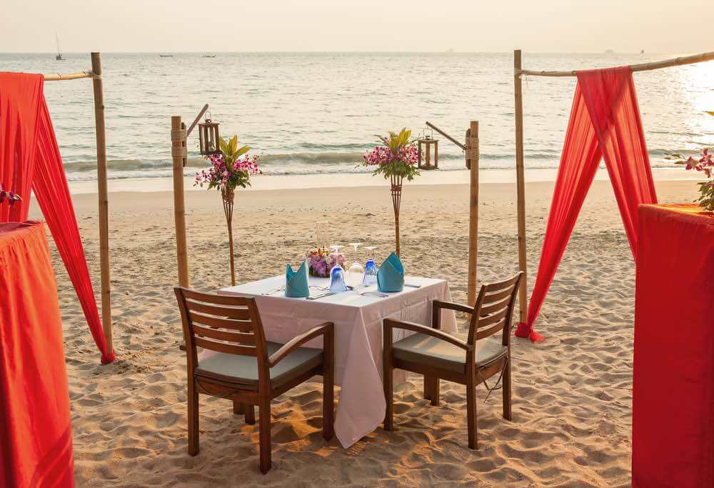 Top 10 Romantic Hawaii Beach Proposal Ideas + Locations featured by top Hawaii blog, Hawaii Travel with Kids: Romantic evening table for two persons on the beach.