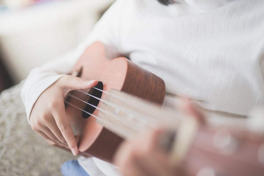 best ukulele for kids featured by top Hawaii blogger, Hawaii Travel with Kids: child playing a beginner ukulele