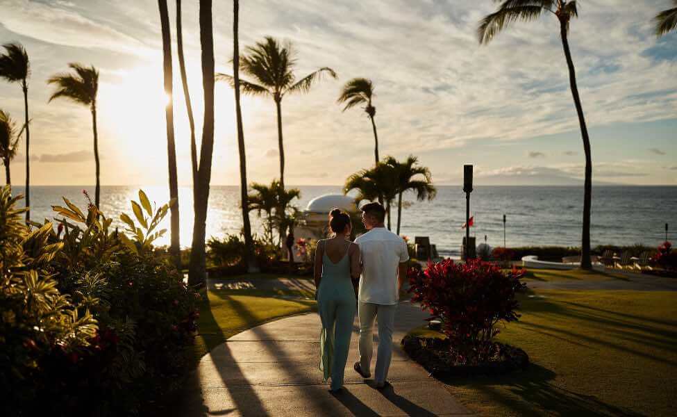 Top 5 Best Maui Luxury Hotels featured by top Hawaii blogger, Hawaii Travel with Kids: The Fairmont Kea Lani is one of the best Maui luxury hotels. Image of a couple walking at this Maui hotel at sunset