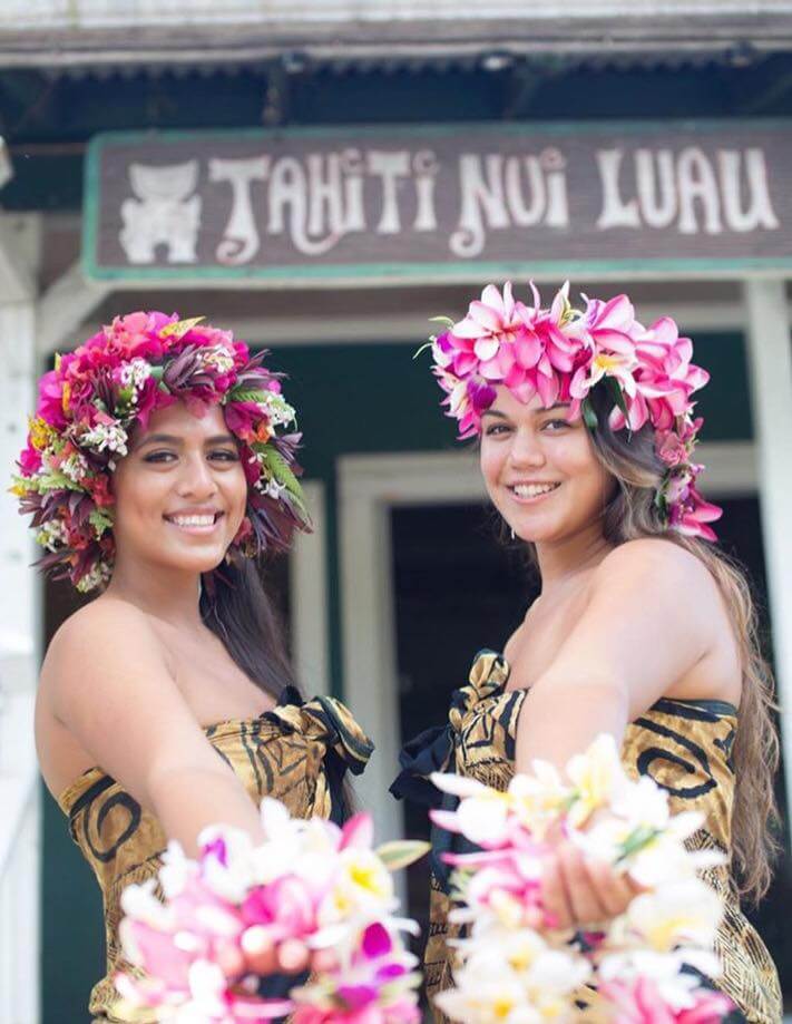 6 Best Kauai Luau Options featured by top Hawaii blogger, Hawaii Travel with Kids: Happy couple having fun running on Hawaii beach vacations in Hawaiian clothing wearing Aloha shirt and pink sarong sun dress and flower leis for traditional wedding or honeymoon concept.