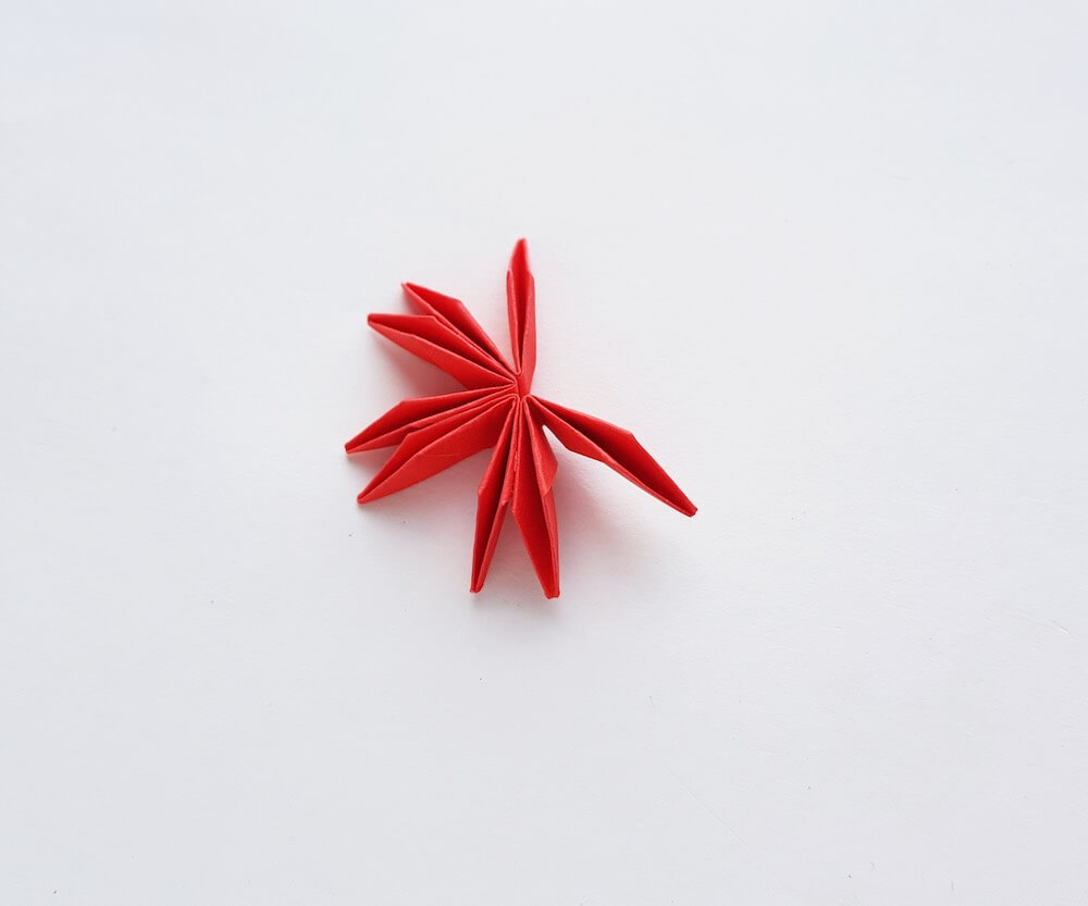 How to Make Origami Poinsettia Flowers, a Hawaiian Christmas craft tutorial featured by top Hawaii blogger, Hawaii Travel with Kids: Image of folded red paper that is glued together