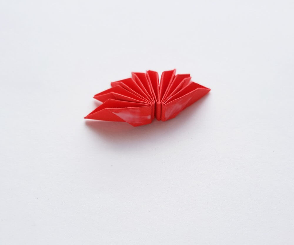 How to Make Origami Poinsettia Flowers, a Hawaiian Christmas craft tutorial featured by top Hawaii blogger, Hawaii Travel with Kids: Image of folded red paper that is glued together