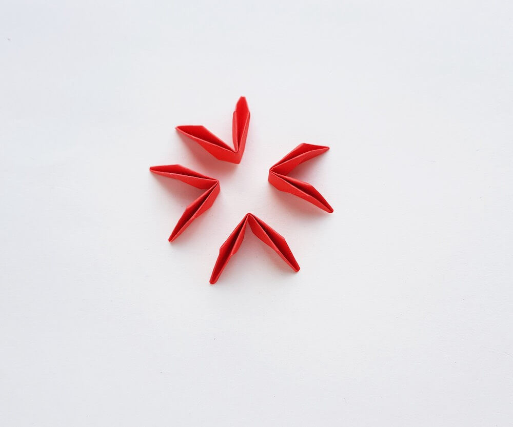 How to Make Origami Poinsettia Flowers, a Hawaiian Christmas craft tutorial featured by top Hawaii blogger, Hawaii Travel with Kids: Image of 4 folded pieces of red paper