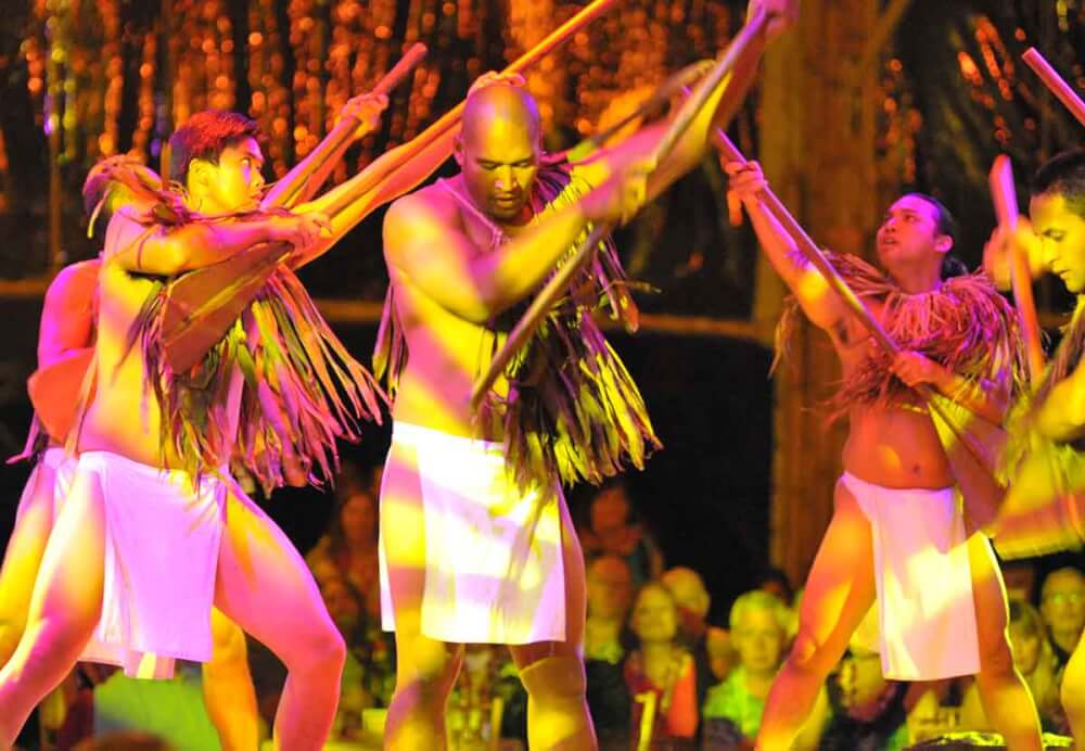 6 Best Kauai Luau Options featured by top Hawaii blogger, Hawaii Travel with Kids: Luau Kalamaku is one of the best Kauai luau. Image of men dancing with sticks