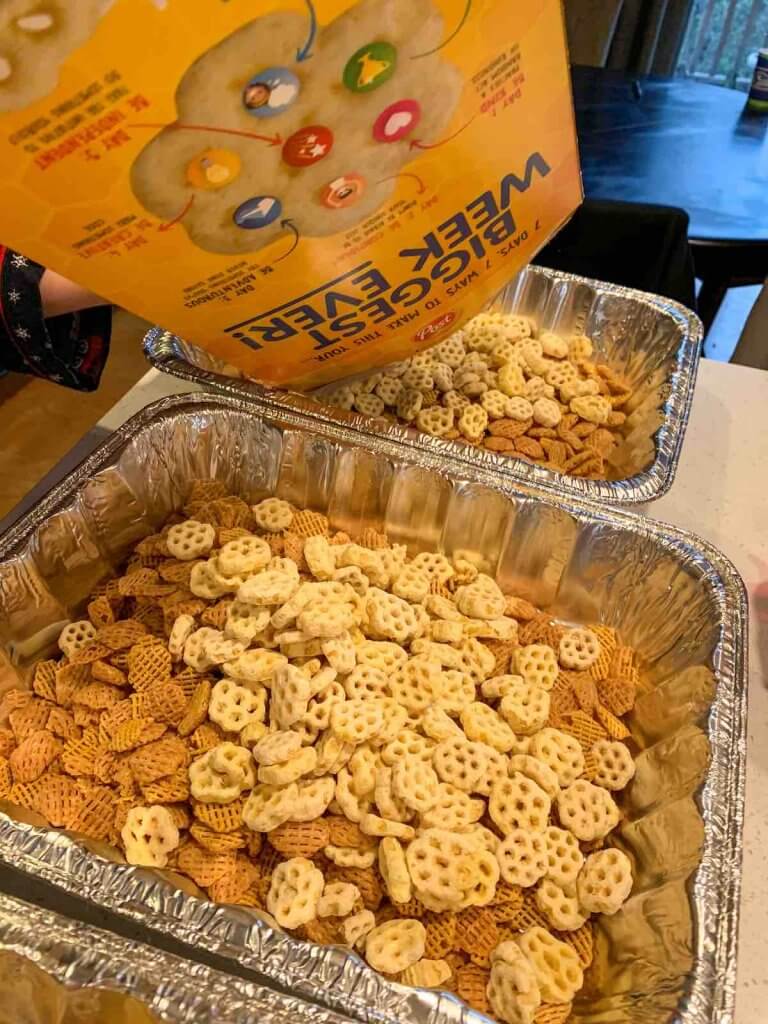 Child pouring Honeycomb cereal in roasting pans to make Hawaiian furikake party mix