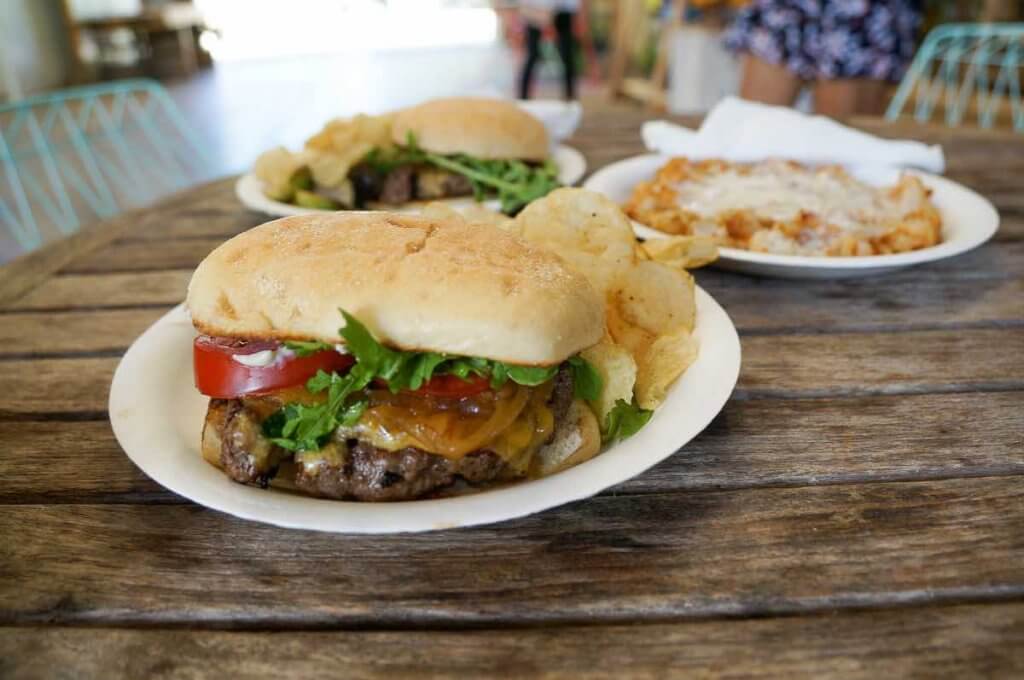 Image of a big burger with cheese, tomatoes, and lettuce.