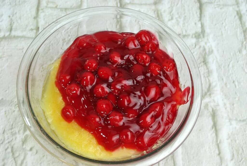 To make Pina Colada Dump Cake, you'll combine the pineapple and cherry pie filling together.