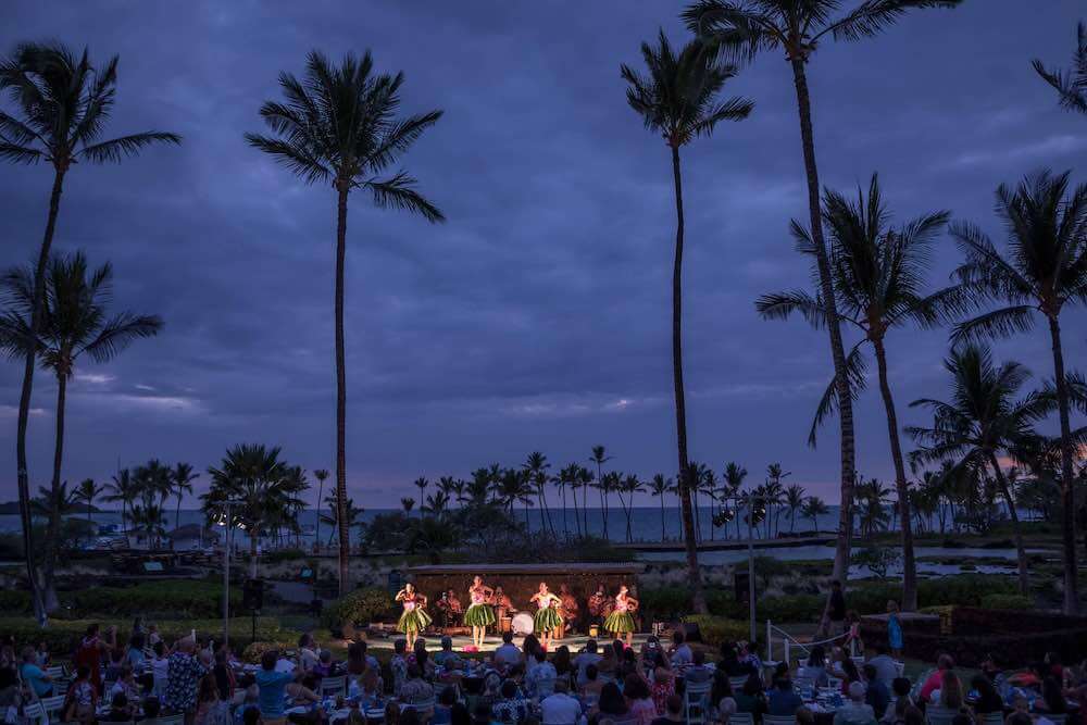 The Sunset Luau is a top Big Island luau at the Waikoloa Beach Marriott Resort and Spa. Image of a luau near resort pools and the ocean at dusk.