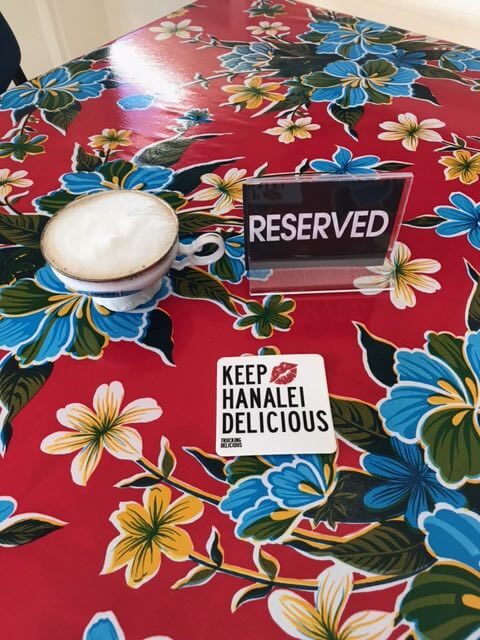 Trucking Delicious is an awesome Kauai food truck. Image of a reserved sign on a table with a sign that says keep Hanalei delicious.