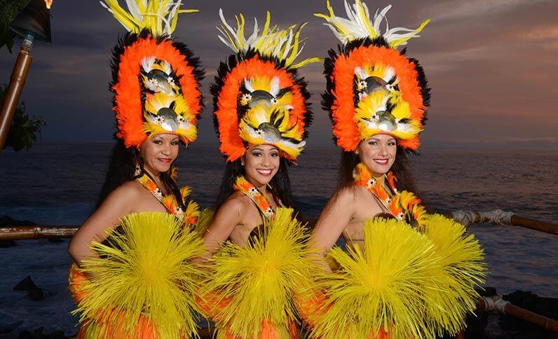 The Voyagers of the Pacific luau is a top Big Island luau to check out. It's at the Royal Kona Resort in Hawaii. Image of 3 Tahitian dancers posing.