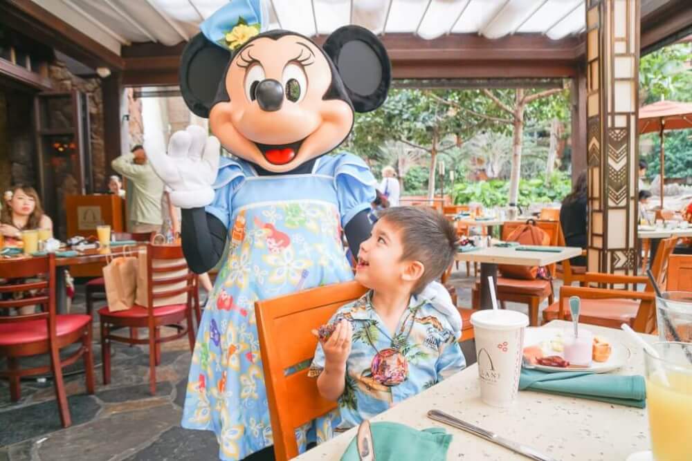 If you're looking for unique things to do with kids in Oahu, head to Aulani Resort to have breakfast with Mickey Mouse! Image of a boy smiling at Minnie Mouse.