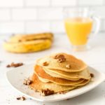 Learn how to make these Dairy Free Banana Pancakes from top Hawaii blog Hawaii Travel with Kids. Image of a plate of banana gluten free pancakes toppd with nuts and syrup.