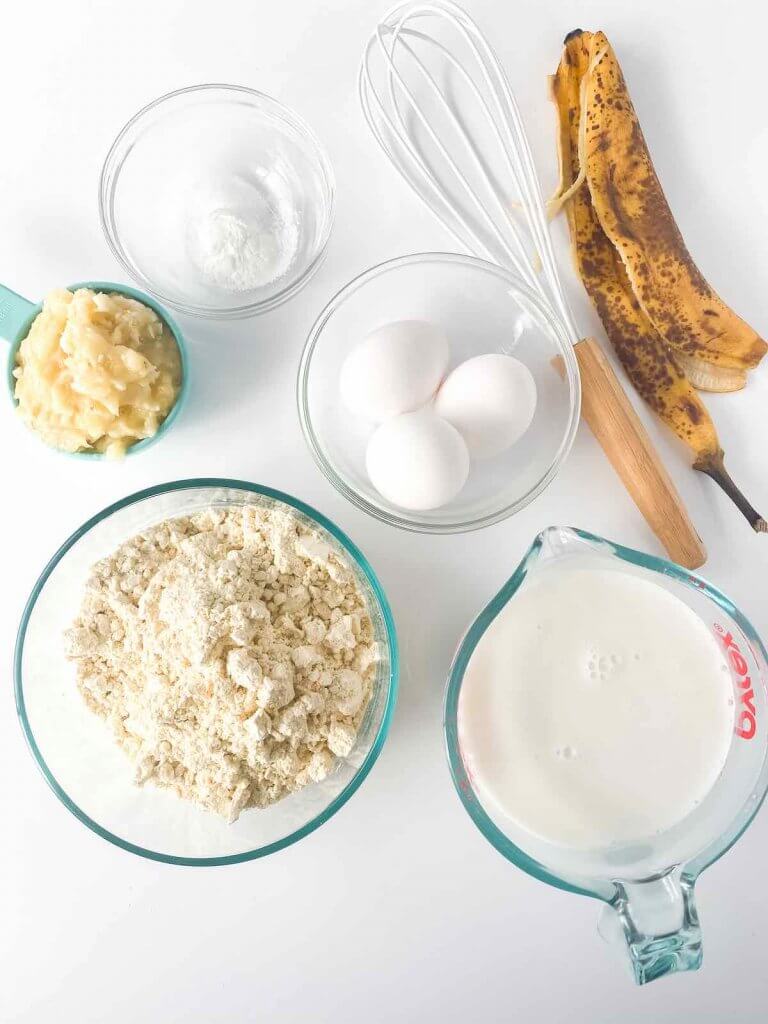 These are the banana pancakes gluten free ingredients you'll need. Image of mashed banana, gluten-free flour, eggs, baking powder, coconut milk, and salt.