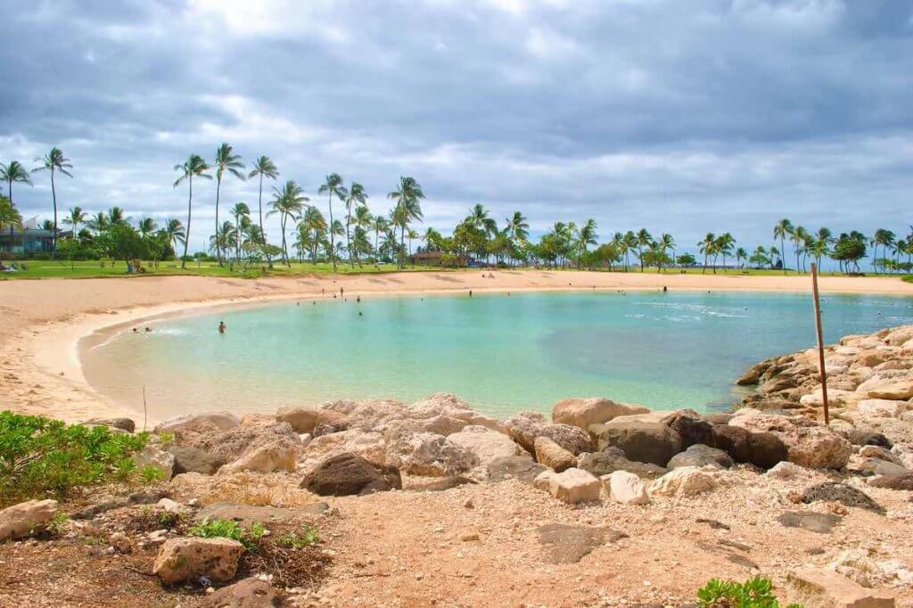 Ko Olina Beach is one of the best beaches on Oahu with kids. Image of a small lagoon with palm trees in the background.